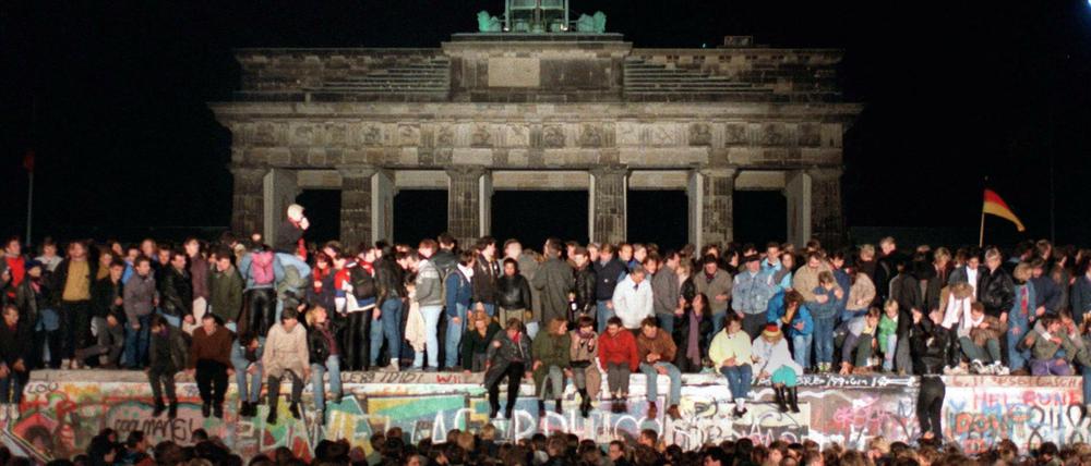 Jubelnde Menschen auf der Berliner Mauer am Brandenburger Tor am 10. November 1989.