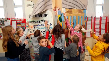 Schülerinnen und Schüler der Grunewald-Schule reißen das Papier ab, mit dem zwei Mauer-Dominosteine verhüllt waren.