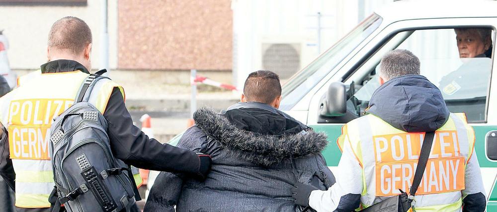 Polizisten begleiten einen Mann, der abgeschoben werden soll (Archivbild).