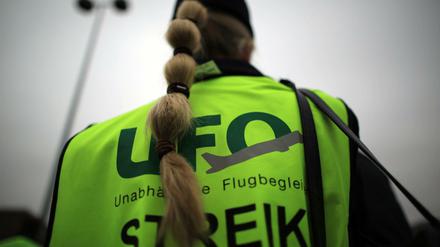 Eine Flugbegleiterin steht vor dem Unternehmenssitz von Eurowings bei einer Kundgebung.