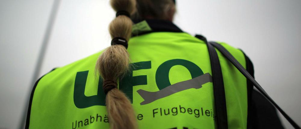 Eine Flugbegleiterin steht vor dem Unternehmenssitz von Eurowings bei einer Kundgebung.