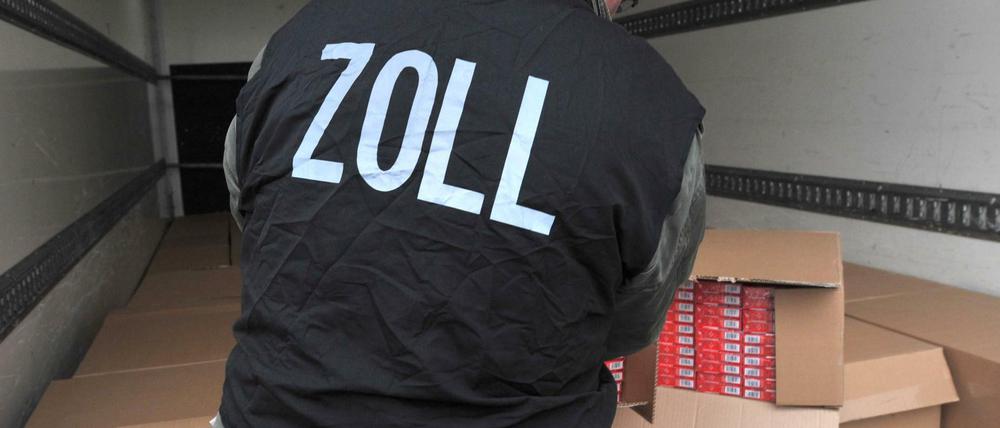 Ein Zollbeamter kontrolliert Kartons mit sichergestellten Zigarettenstangen (Symbolbild).
