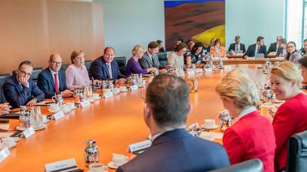 Kanzlerin und Minister sitzen zu Beginn der Sitzung des Bundeskabinetts im Kanzleramt am Kabinettstisch.