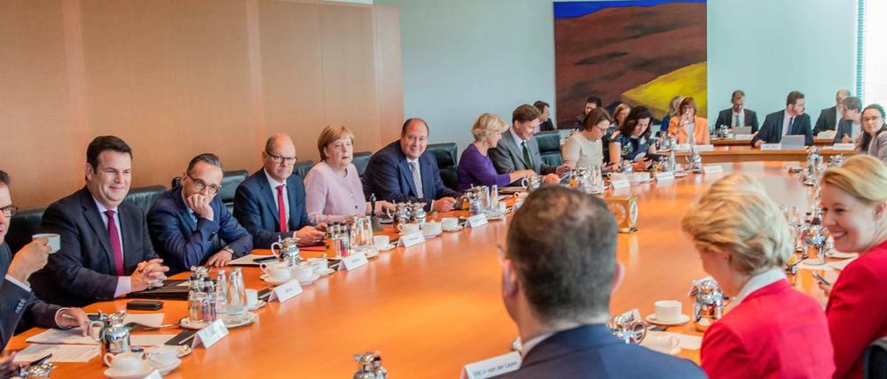Kanzlerin und Minister sitzen zu Beginn der Sitzung des Bundeskabinetts im Kanzleramt am Kabinettstisch.