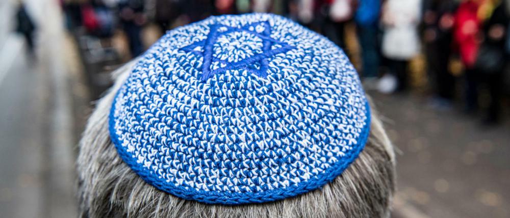 Ein Mann mit Kippa steht vor der Neuen Synagoge in Berlin vor einer Menschenkette.
