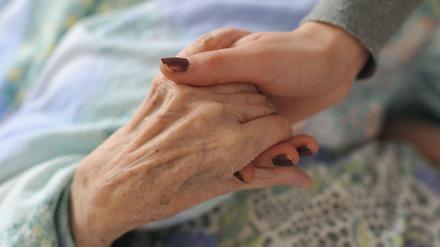 Finanziell entlastet: Eine junge Frau hält die Hand einer Heimbewohnerin.