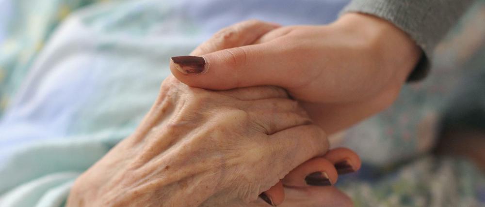 Finanziell entlastet: Eine junge Frau hält die Hand einer Heimbewohnerin.
