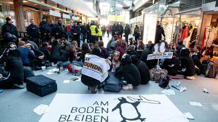 Demonstranten des Bündnisses "Am Boden bleiben" blockieren die Haupthalle des Flughafen Tegels. Die Aktivisten wollen damit auf die Klimaschäden durch den Flugverkehr aufmerksam machen.