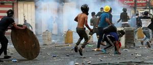 Demonstranten in Bagdad stehen in einer Wolke aus Tränengas.