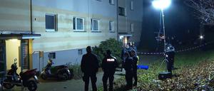 Polizisten stehen vor einem Wohnhaus. Ein Unbekannter hat in der Nacht eine Frauenleiche an der Straße eines Wohngebiets abgelegt.