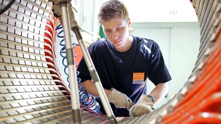 Traditionelle Industriefertigung - hier im Dynamowerk von Siemens in Berlin-Spandau: Ein Mitarbeiter beim Einschieben von Nutverschluessen im Stator des späteren Dynamos. 