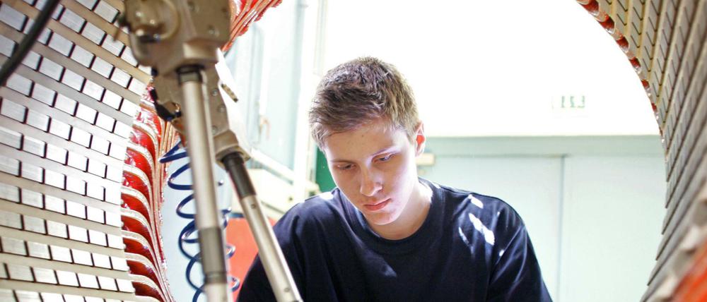 Traditionelle Industriefertigung - hier im Dynamowerk von Siemens in Berlin-Spandau: Ein Mitarbeiter beim Einschieben von Nutverschluessen im Stator des späteren Dynamos. 