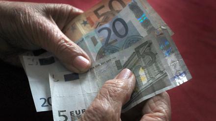 Eine 83-jährige Frau hält verschiedene Euronoten in der Hand.