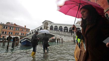 In Venedig gehen Passanten in der Nähe der Rialto-Brücke durch das Hochwasser.