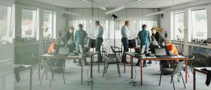 Mitarbeiter unterhalten sich an einem Arbeitstisch in einem Coworking-Space.