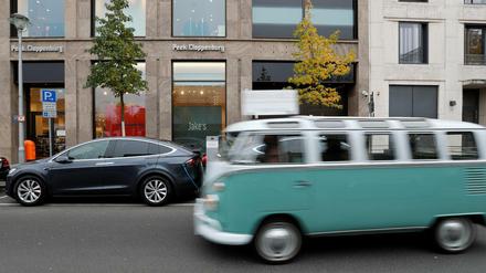 Ein Oldtimer von VW fährt an einem Tesla in Berlin vorbei 