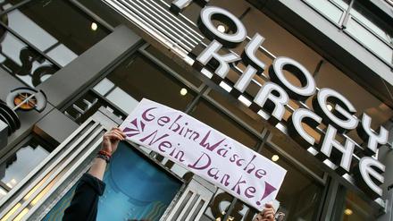 Eröffnung in Berlin 2007. Eine Frau protestiert vor der Scientology-Dependance mit einem Schild "Gehirnwäsche - Nein Danke !". 