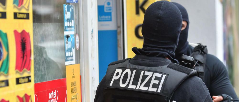 Vermummte Einsatzkräfte stehen vor einem Kiosk im Stadtteil Neukölln.