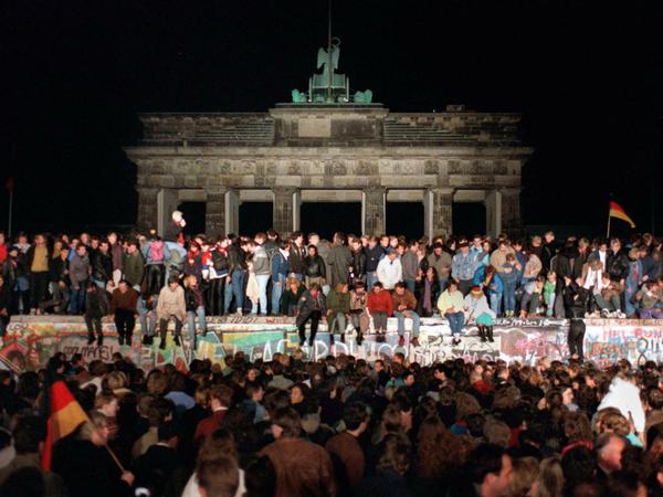 Jubelnde Menschen auf der Berliner Mauer am Brandenburger Tor am 10. November 1989.