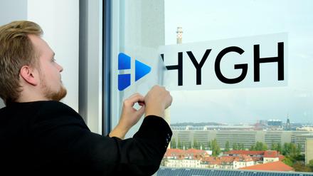 HYGH-Hardware-Chef Antonius Link klebt einen Aufkleber mit Firmenlogo an ein Bürofenster.