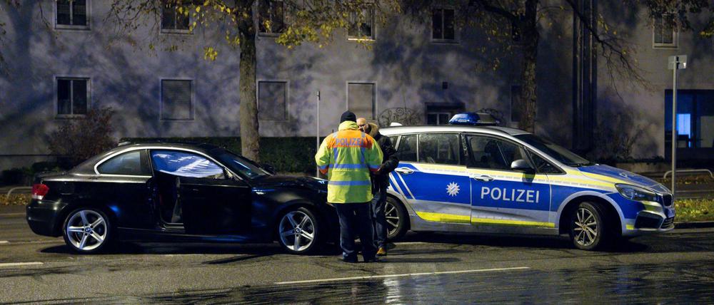 Polizisten stehen in München an einem beschädigten Auto.