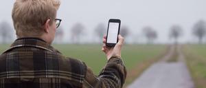 Ein Mann lässt sein Smartphone nach Netzbetreibern suchen.