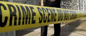 Ein US-amerikanischer Polizist läuft hinter einem Absperrband entlang (Illustration).