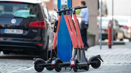 E-Tretroller stehen auf dem Bürgersteig neben einem Parkscheinautomat.