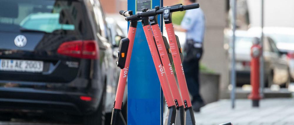 E-Tretroller stehen auf dem Bürgersteig neben einem Parkscheinautomat.
