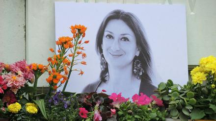 Kerzen und Blumen stehen vor einem Foto der ermordeten Journalistin Caruana Galizia.