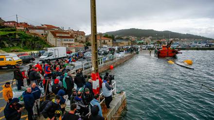 Einwohner der Gemeinde Aldan beobachten einen Einsatz, bei dem zwei Schlepper ein Drogen-U-Boot aus dem Wasser ziehen.