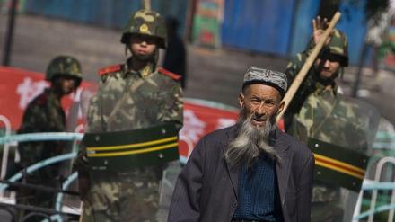 Ein Angehöriger der uigurischen Minderheit geht in der Unruheregion Xinjiang an chinesischen Sicherheitskräften vorbei.