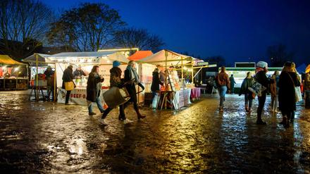 Besucher gehen während der blauen Stunde über den Flohmarkt im Mauerpark in Berlin.