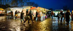 Besucher gehen während der blauen Stunde über den Flohmarkt im Mauerpark in Berlin.