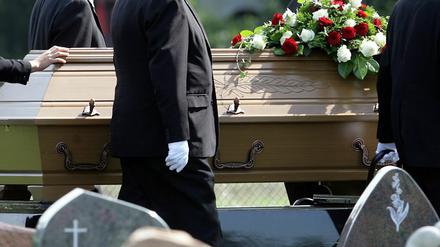 Sargträger tragen einen Sarg auf den Friedhof.