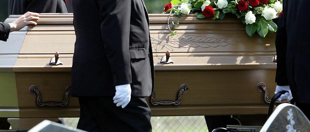 Sargträger tragen einen Sarg auf den Friedhof.