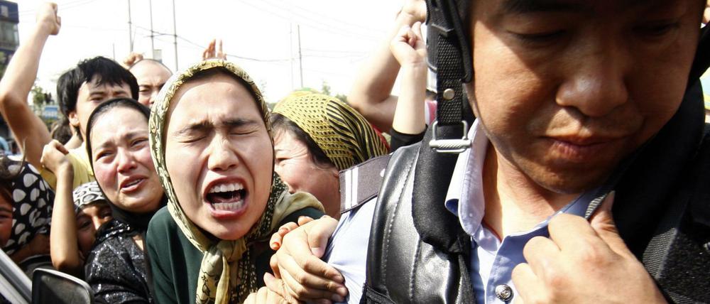 Eine Angehörige der uigurischen Minderheit in China versucht einen Polizisten zu packen, während einer Demonstration in Ürümqi in der Unruheregion Xinjiang in Nordwestchina.