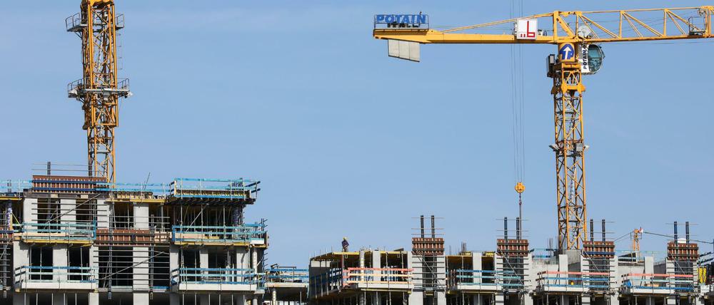 Kräne stehen auf einer Baustelle für mehrstöckige Wohnhäuser.