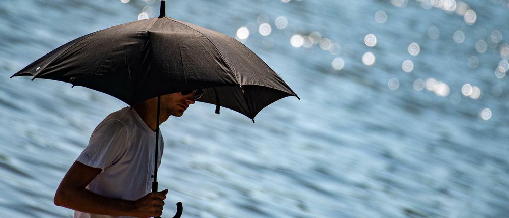 Ein Mann schützt sich in Göttingen mit einem Regenschirm vor der Sonne (Symbolbild).