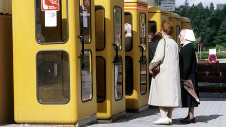 Als es noch keine Smartphones gab. Personen warten vor einer gelben Telefonzelle, 1985.