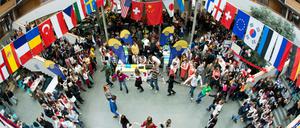 Studierende tanzen unter internationalen Flaggen in einem Hochschulauditorium.