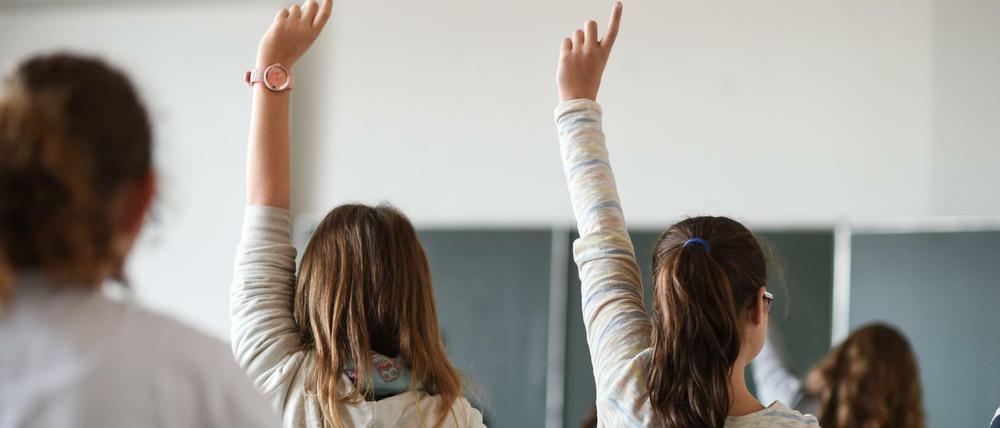 Schülerinnen sitzen in einem Klassenraum und melden sich.