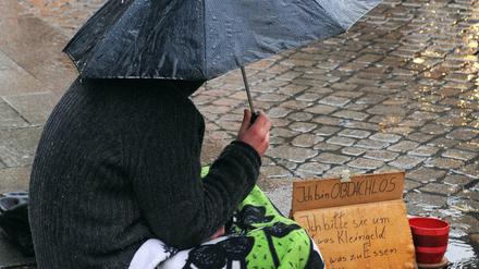 Ein Obdachloser sitzt im strömenden Regen in der Innenstadt von Bremen.