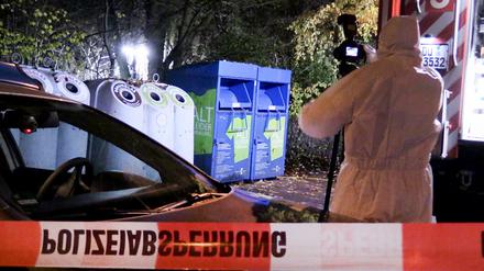Ein Mitarbeiter der Spurensicherung fotografiert vor Glas- und Kleidercontainer am Rand eines Waldes in Duisburg.