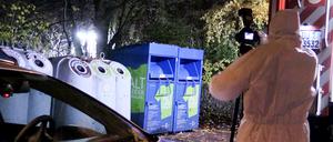 Ein Mitarbeiter der Spurensicherung fotografiert vor Glas- und Kleidercontainer am Rand eines Waldes in Duisburg.