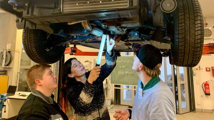 Bildungssenatorin Sandra Scheeres inspiziert mit zwei Berufsschülern ein Auto im OSZ für Kraftfahrzeugtechnik.