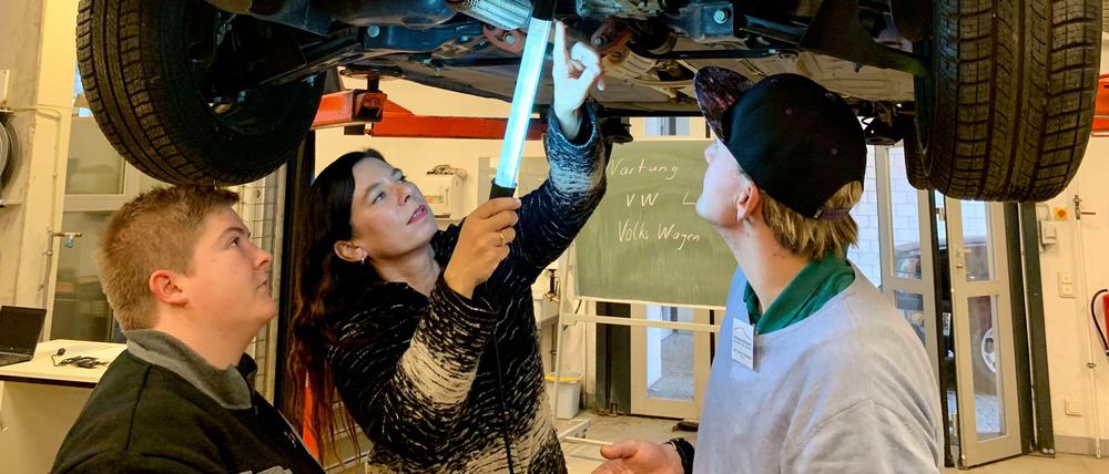 Bildungssenatorin Sandra Scheeres inspiziert mit zwei Berufsschülern ein Auto im OSZ für Kraftfahrzeugtechnik.