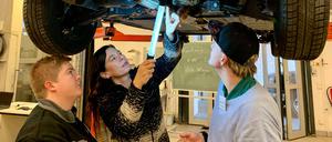 Bildungssenatorin Sandra Scheeres inspiziert mit zwei Berufsschülern ein Auto im OSZ für Kraftfahrzeugtechnik.