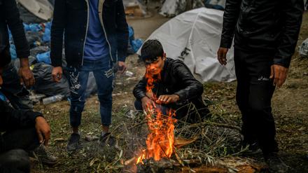 Migranten versuchen sich an einem kleinen Feuer in einem Zwischenlager neben dem Lager Moria auf der Insel Lesbos aufzuwärmen.