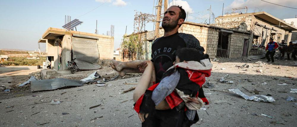 Ein Mann trägt ein verletztes Mädchen nach einem Bombenangriff in Syrien.